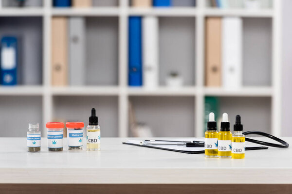 bottles with medical cannabis and cbd lettering near clipboard on desk in clinic