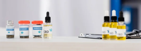 bottles with medical cannabis and cbd lettering near clipboard on desk in clinic, banner