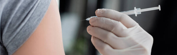 Cropped view of doctor holding syringe near patient, banner 