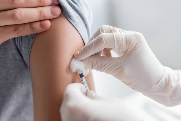 Cropped view of doctor in latex gloves doing vaccination of patient in hospital 