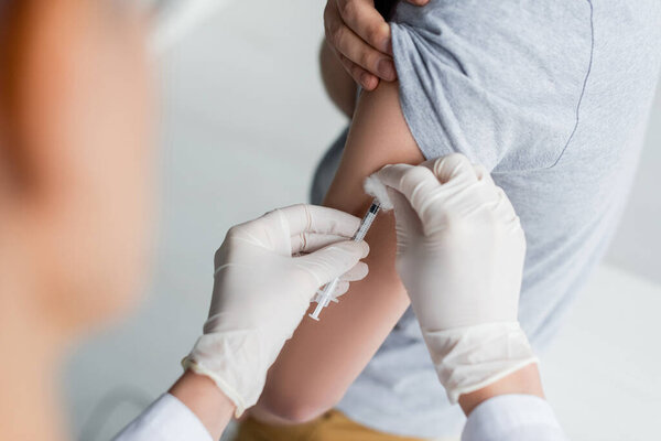 Cropped view of doctor with cotton doing vaccination of patient 