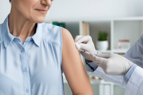 Cropped view of doctor doing vaccination of mature woman 