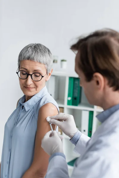 在注射疫苗期间站在医生旁边的成年病人 — 图库照片