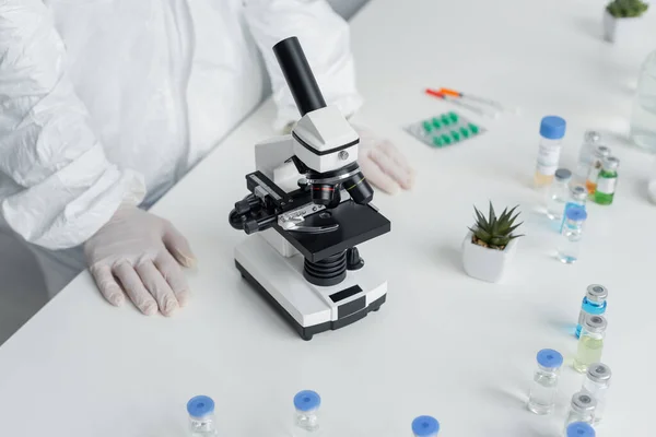 Cropped View Scientist Hazmat Suit Standing Microscope Vaccines Table — Stock Photo, Image