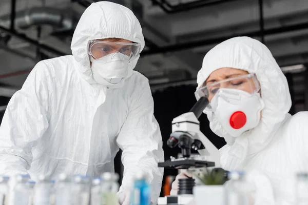 Scientist Standing Colleague Using Microscope Vaccines Blurred Foreground — Φωτογραφία Αρχείου