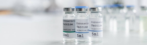 Close up view of jars with coronavirus vaccines in laboratory, banner 