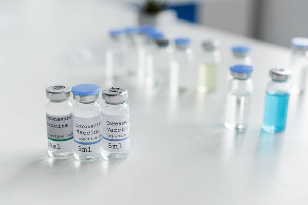 Jars with coronavirus vaccine lettering on table in laboratory 