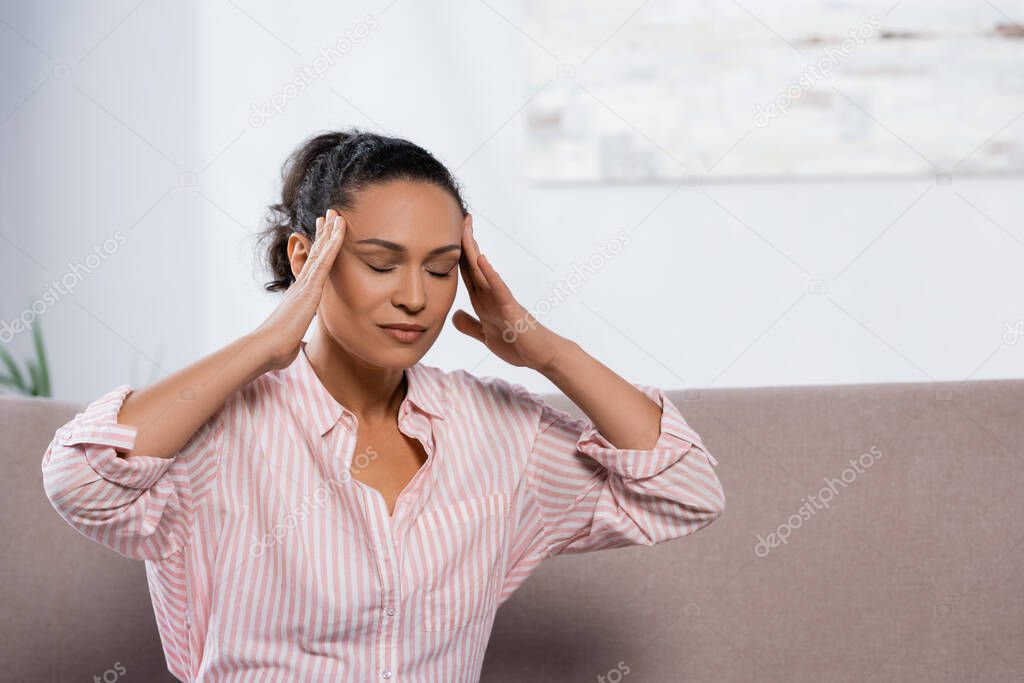 african american woman suffering from headache in living room 