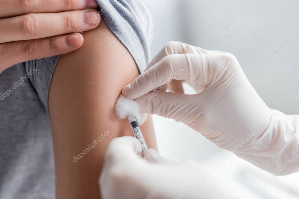 Cropped view of doctor in latex gloves doing vaccination of patient in hospital 