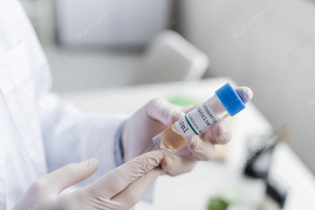 Cropped view of doctor in white coat and latex gloves holding vaccine 