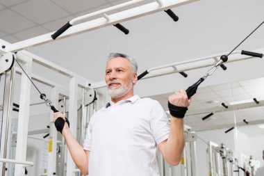 Fiziksel rehabilitasyon sırasında hastane spor salonunda çalışan gülümseyen adam