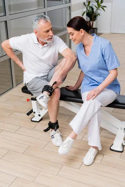 mature man talking to physical instructor in rehabilitation center