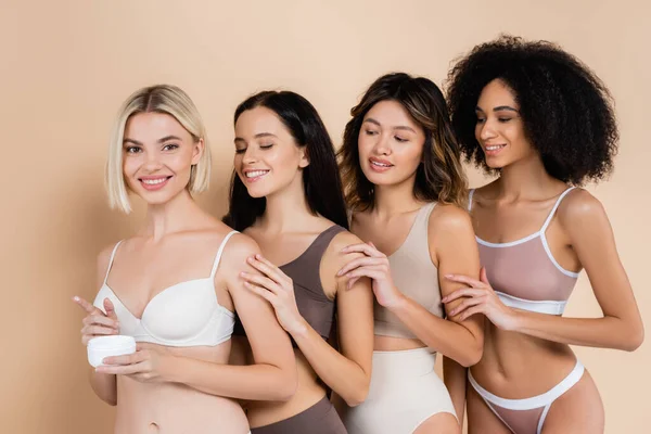 Cheerful Woman Holding Cosmetic Cream Interracial Friends Beige — Stock Photo, Image