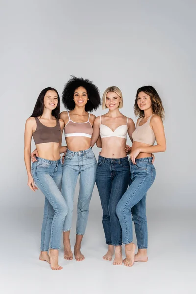 Full Length View Multicultural Women Bras Jeans Smiling Camera Grey — Stock Photo, Image