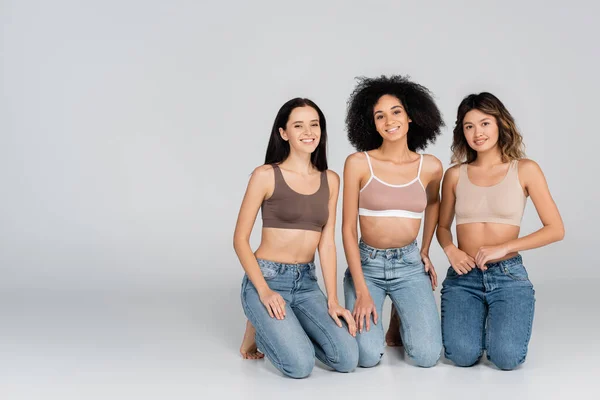 Gelukkig Interraciale Vrouwen Beha Jeans Kijken Naar Camera Grijs — Stockfoto