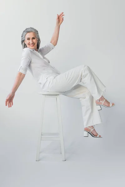 Mulher Madura Feliz Olhando Para Câmera Cadeira Fundo Cinza — Fotografia de Stock