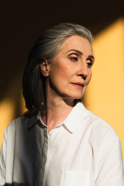 Серая женщина смотрит на желтый фон с тенью 