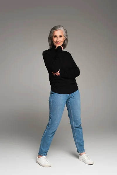 Full Length Mature Woman Jeans Turtleneck Looking Camera Grey Background — Stock Photo, Image