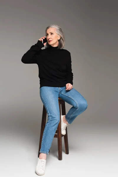 Grey Haired Woman Talking Smartphone Chair Grey Background — Stock Photo, Image