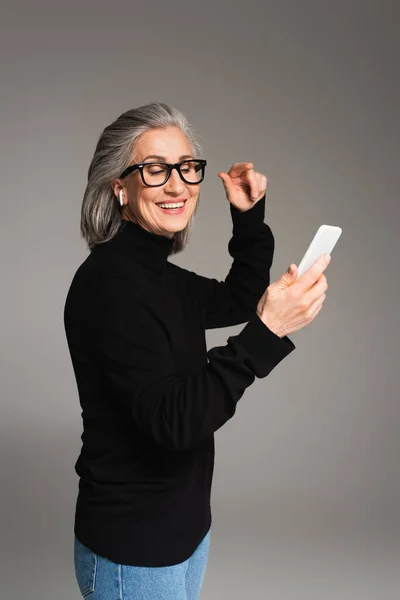 Mulher Madura Alegre Fone Ouvido Usando Smartphone Isolado Cinza — Fotografia de Stock