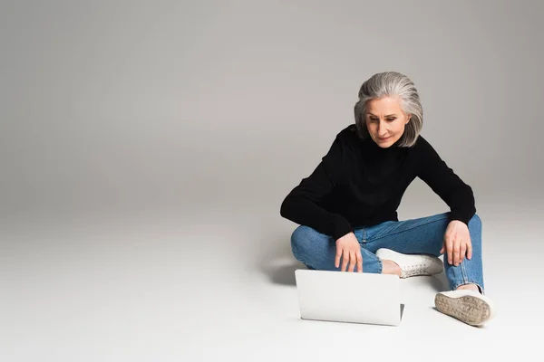 Μεσήλικη Γυναίκα Που Χρησιμοποιεί Φορητό Υπολογιστή Γκρι Φόντο — Φωτογραφία Αρχείου