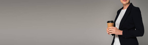 Обрезанный вид предпринимательницы, держащей бумажный стаканчик изолированный на сером, баннер 