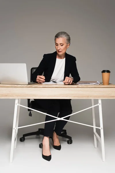 Mature Businesswoman Looking Notebook Devices Coffee Grey Background — Stock Photo, Image