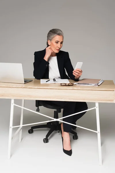 Mujer Negocios Madura Usando Teléfono Inteligente Cerca Computadora Portátil Documentos — Foto de Stock