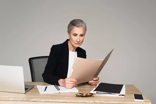 Zakenvrouw Zoek Naar Documenten Buurt Van Apparaten Tafel Geïsoleerd Grijs — Stockfoto