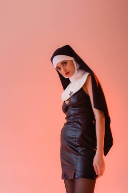 young nun in sexy dress looking at camera isolated on pink clipart