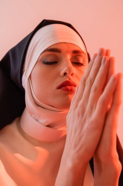 Genç rahibe pembe gözleri kapalı dua ediyor.