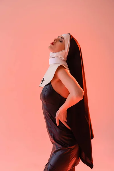 若いです修道女で革のドレス姿ピンクに隔離された目でポーズ — ストック写真