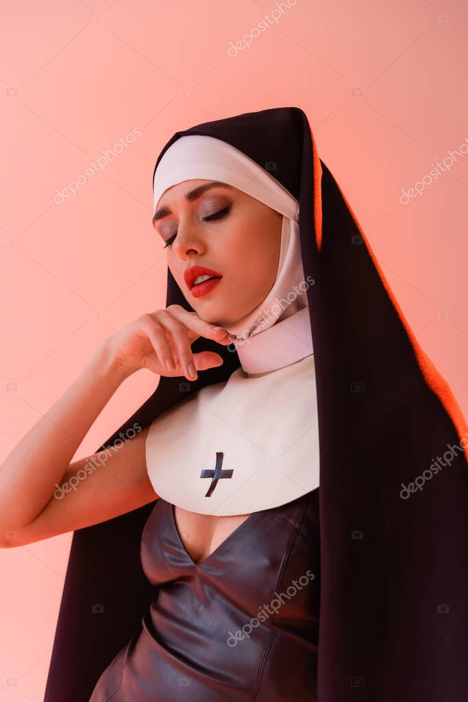 Сексуальная монахиня касаясь лица, позируя с закрытыми глазами изолированы ...