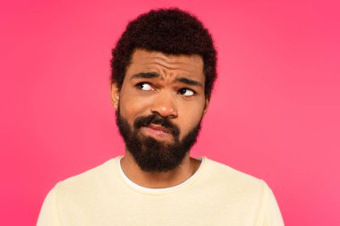 Kafası karışmış Afrikalı Amerikalı bir adam pembe üzerine izole edilmiş.