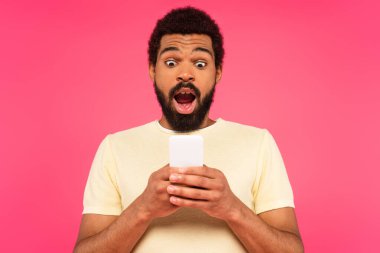 Pembe üzerine izole edilmiş akıllı telefon kullanan Afro-Amerikan adam şok oldu.