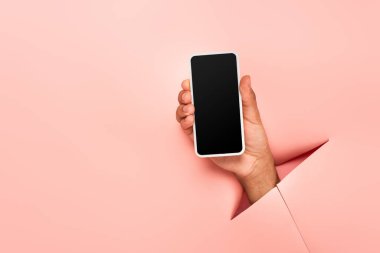 Pembe arka planda beyaz ekranlı akıllı telefonu olan Afro-Amerikan bir adamın kısmi görüntüsü 