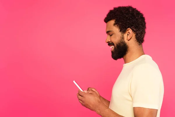 从侧面看快乐的非洲裔美国人使用的智能手机是粉红色的 — 图库照片