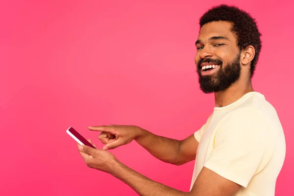 Heureux Homme Afro Américain Pointant Vers Smartphone Isolé Sur Rose — Photo