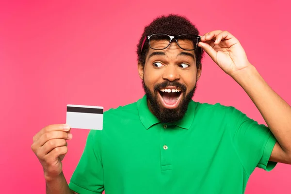 Erstaunt Afrikanisch Amerikanischer Mann Mit Brille Schaut Auf Kreditkarte Isoliert — Stockfoto