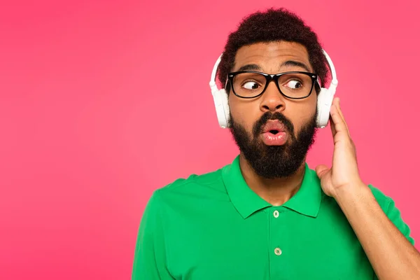 Geschokt Afro Amerikaanse Man Bril Draadloze Hoofdtelefoon Geïsoleerd Roze — Stockfoto