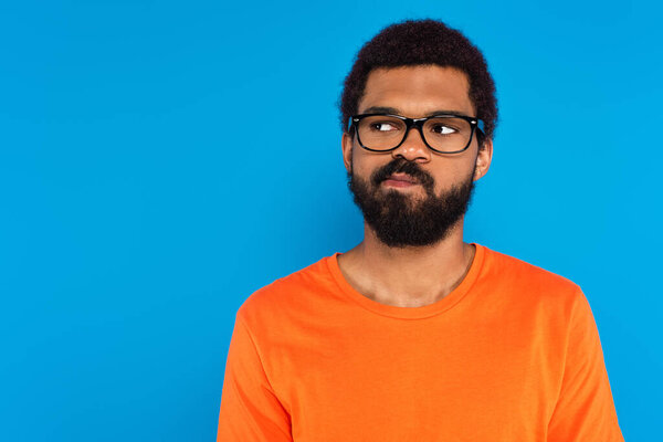 uncertain african american man in glasses isolated on blue