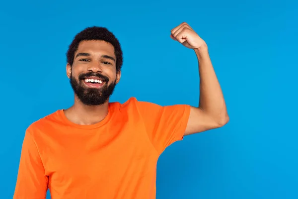 Bebaarde Afro Amerikaanse Man Glimlachen Tonen Spier Geïsoleerd Blauw — Stockfoto