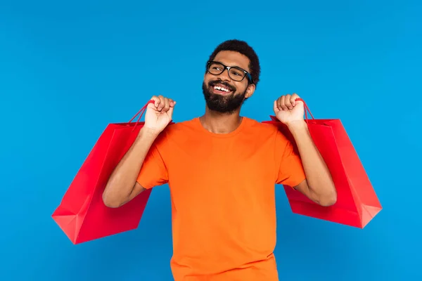 Hombre Afroamericano Complacido Gafas Que Sostienen Bolsas Aisladas Azul —  Fotos de Stock