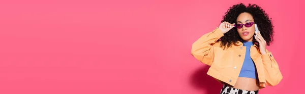 Кучерява Афроамериканська Жінка Сонцезахисних Окулярах Говорить Смартфоні Рожевому Банер — стокове фото