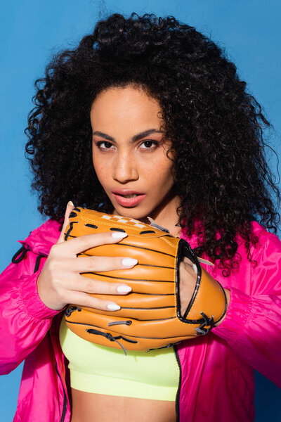 sporty african american woman wearing leather baseball glove isolated on blue