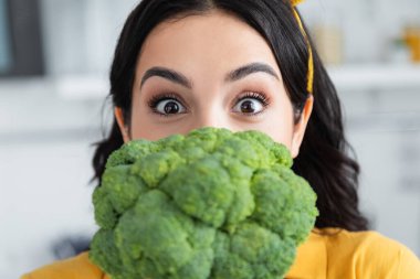 brunette woman looking at camera near ripe broccoli  clipart