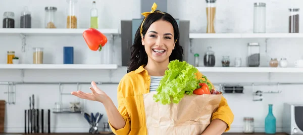 快乐的黑发女人 拿着装有食品杂货和横幅的纸袋 放着风铃辣椒 — 图库照片