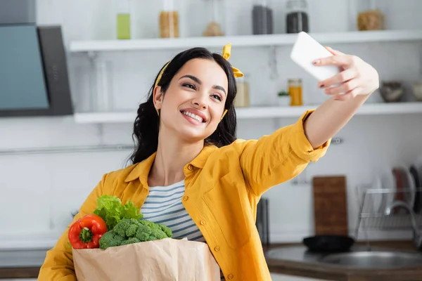 Alegre Morena Mujer Sosteniendo Bolsa Papel Con Comestibles Tomando Selfie — Foto de Stock