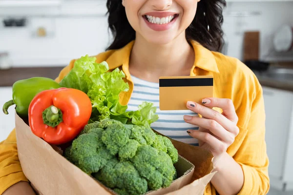 Vista Recortada Mujer Feliz Sosteniendo Bolsa Papel Con Comestibles Tarjeta — Foto de Stock