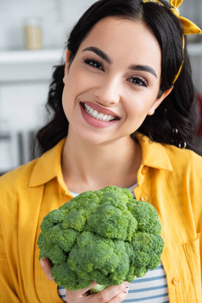 happy brunette woman holding ripe green broccoli 
